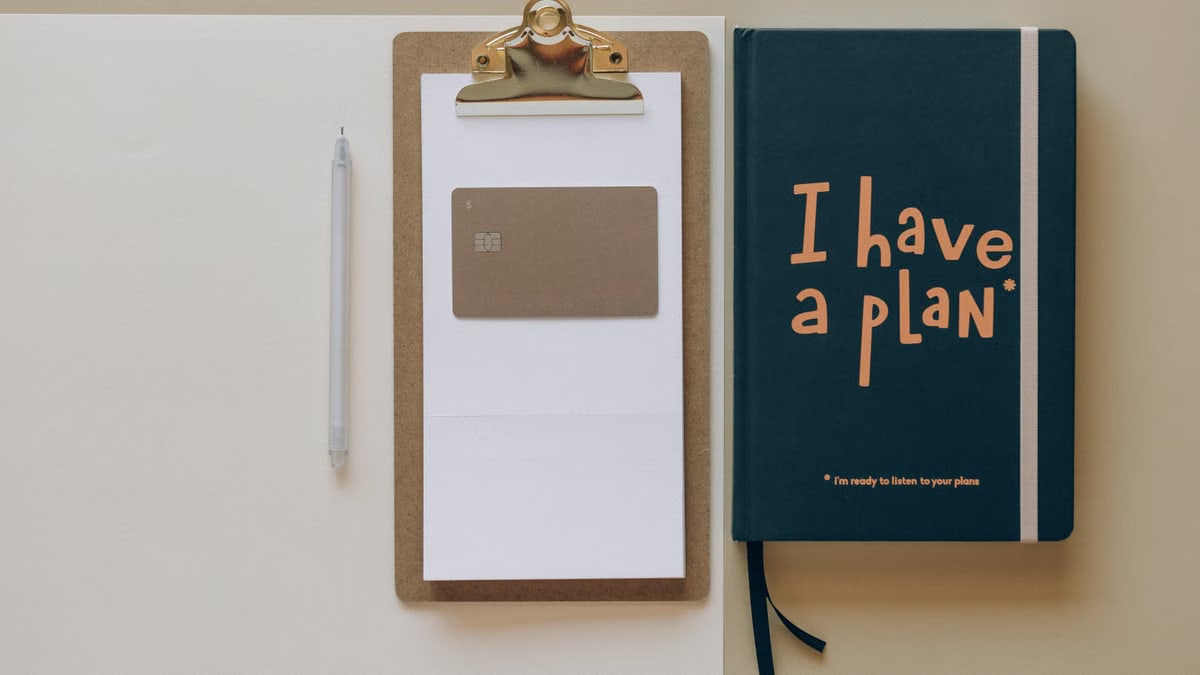 A minimalist office setup featuring a planner, clipboard, card, and pen, perfect for planning and organization.